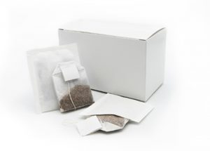 White box with various custom tea bags, including a pyramid tea bag, a flat tea bag, and a sachet, made by Custom Co-Pak, a private label tea packaging company in the USA.