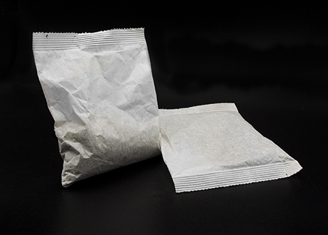 Two sealed tea sachets on a black background, packaged by Custom Co-Pak, a private label tea packaging company in the USA